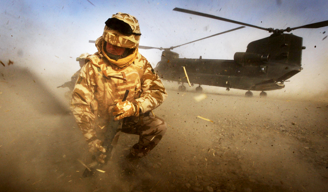 British soldier kneeling in front of Chinook helicopter